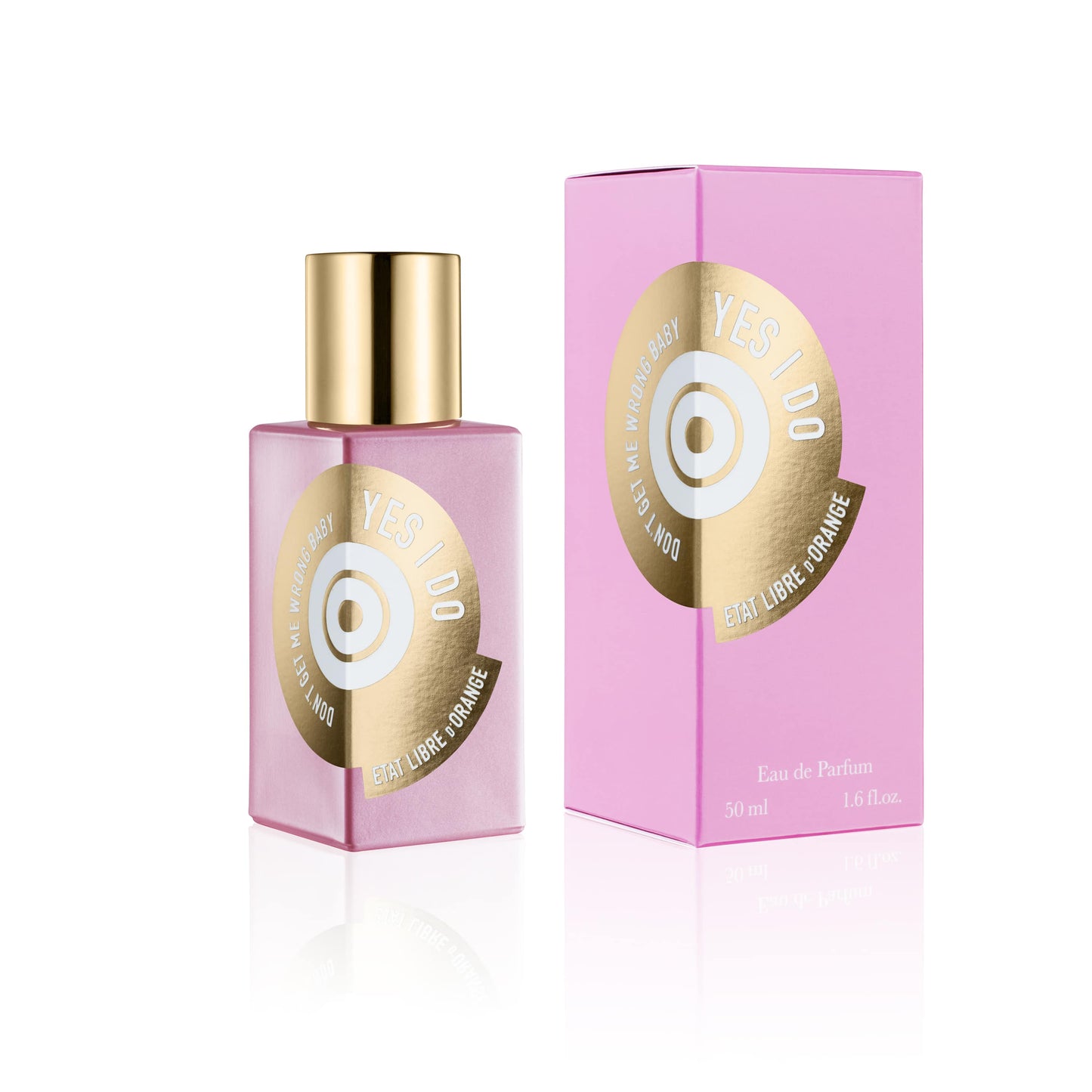 Image of Etat Libre d'Orange Yes I Do Eau de Parfum in a pink rectangular glass perfume bottle with a gold spray nozzle cap. The bottle has a circular label with gold foil text reading "Yes I Do" and "Etat Libre d'Orange", and the phrase "DON'T GET ME WRONG BABY" written in white around the circle's edge. Behind the bottle is a pink rectangular box with a similar label. Both are reflected on a white glossy surface.